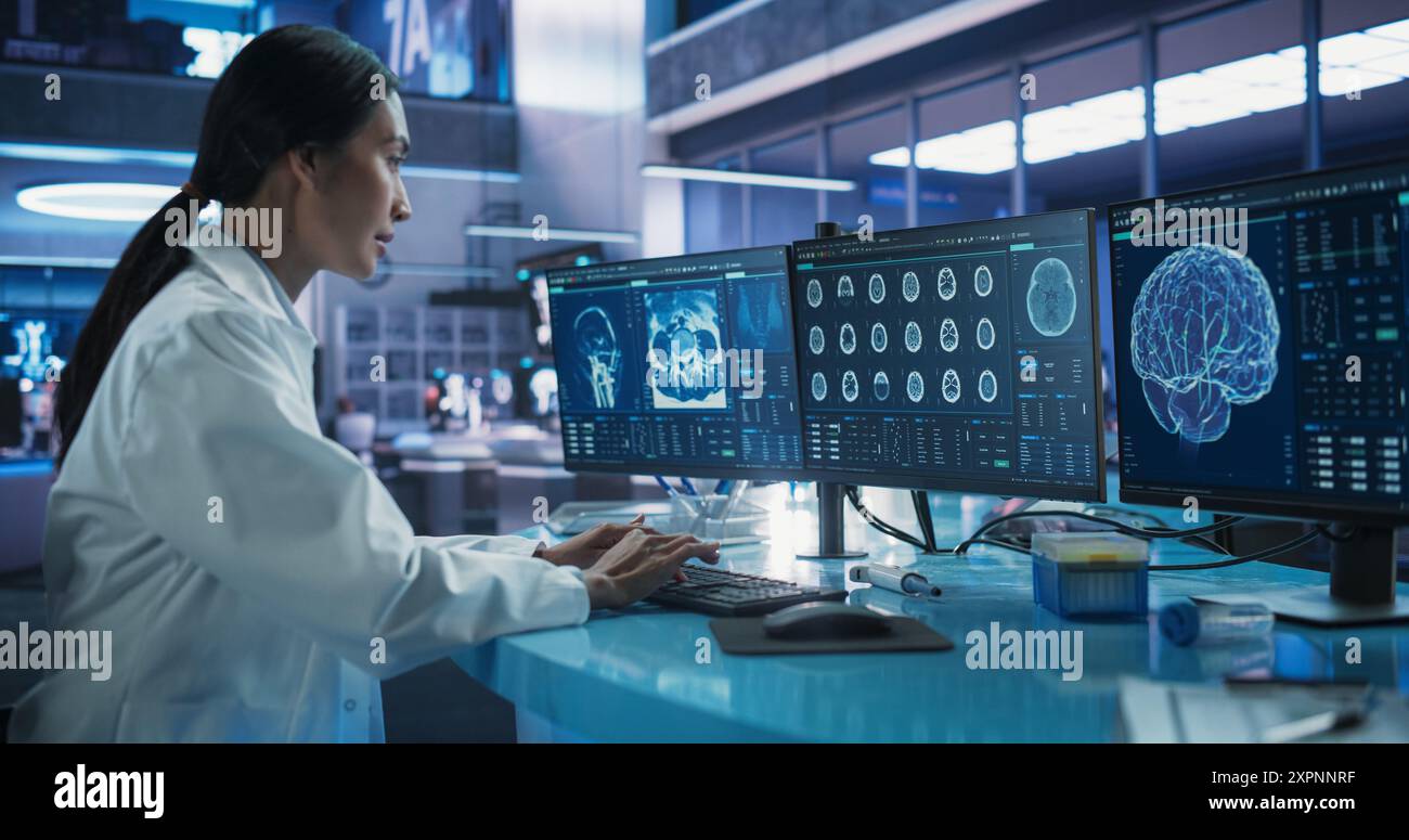 Krankenhausforschungslabor: Asiatische Wissenschaftlerin mit Computer mit Brain Scan MRT-Bildern. Professioneller Neurologe, der CT-Scan analysiert und die Behandlung von Patienten mit Hirnschäden findet. Stockfoto