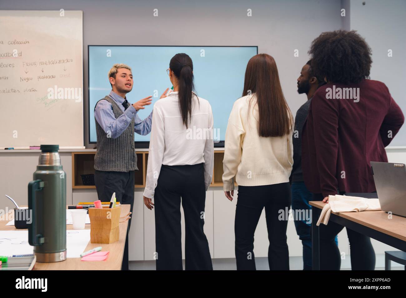 Leute versammelten sich im Büro in einer Werkstatt, es gibt einen Mann, der die Werkstatt leitet und den anderen Leuten vor ihm erklärt. Stockfoto