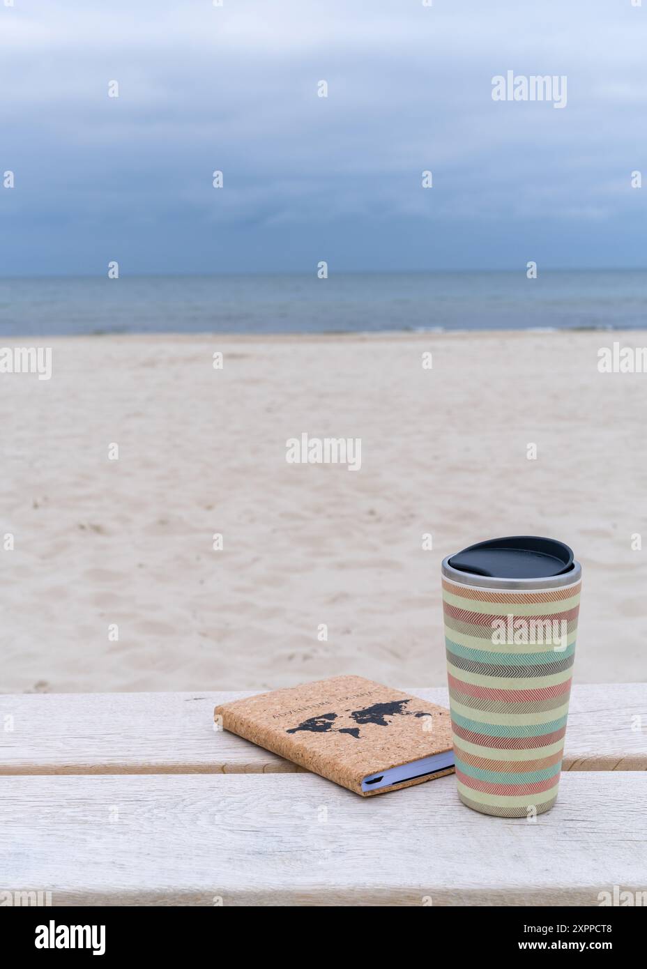 Nahaufnahme eines Glases Kaffee mit einem Notizblock auf einer hellen Bank vor dem Hintergrund des Meeres. Kopierbereich. Stockfoto
