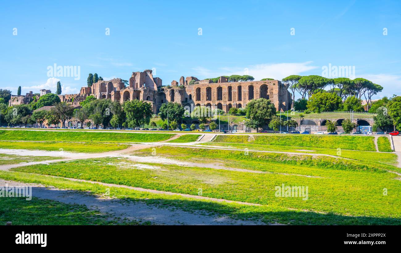 Blick auf die Ruinen des Domus Severiana auf dem Palatin vom Circus Maximus in Rom, Italien. Der antike römische Palast ist in der Ferne sichtbar, mit einem grasbewachsenen Bereich im Vordergrund. Stockfoto