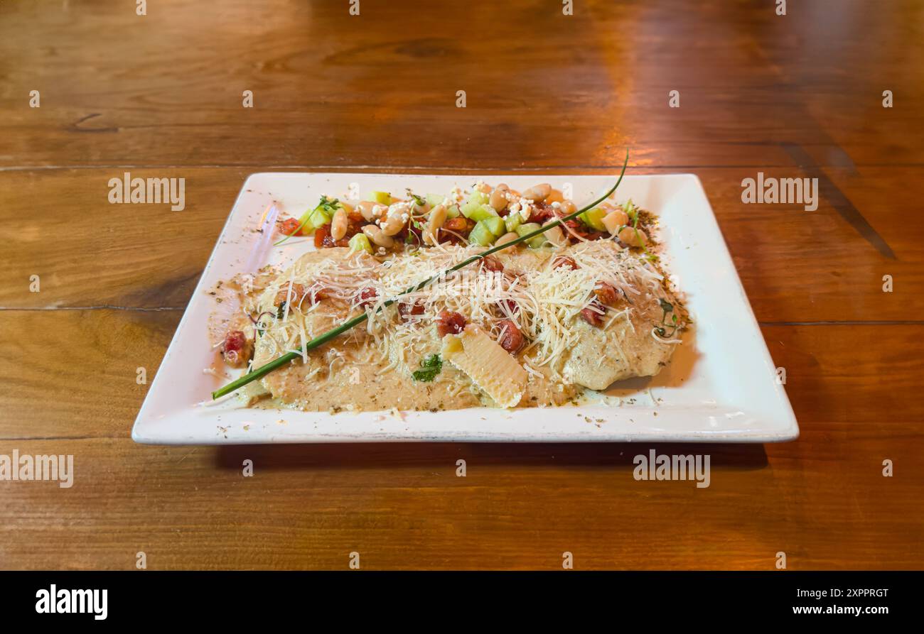 Kurzes Rib-Ravioli-Hauptgericht und Salat auf rustikalem Holztisch Stockfoto