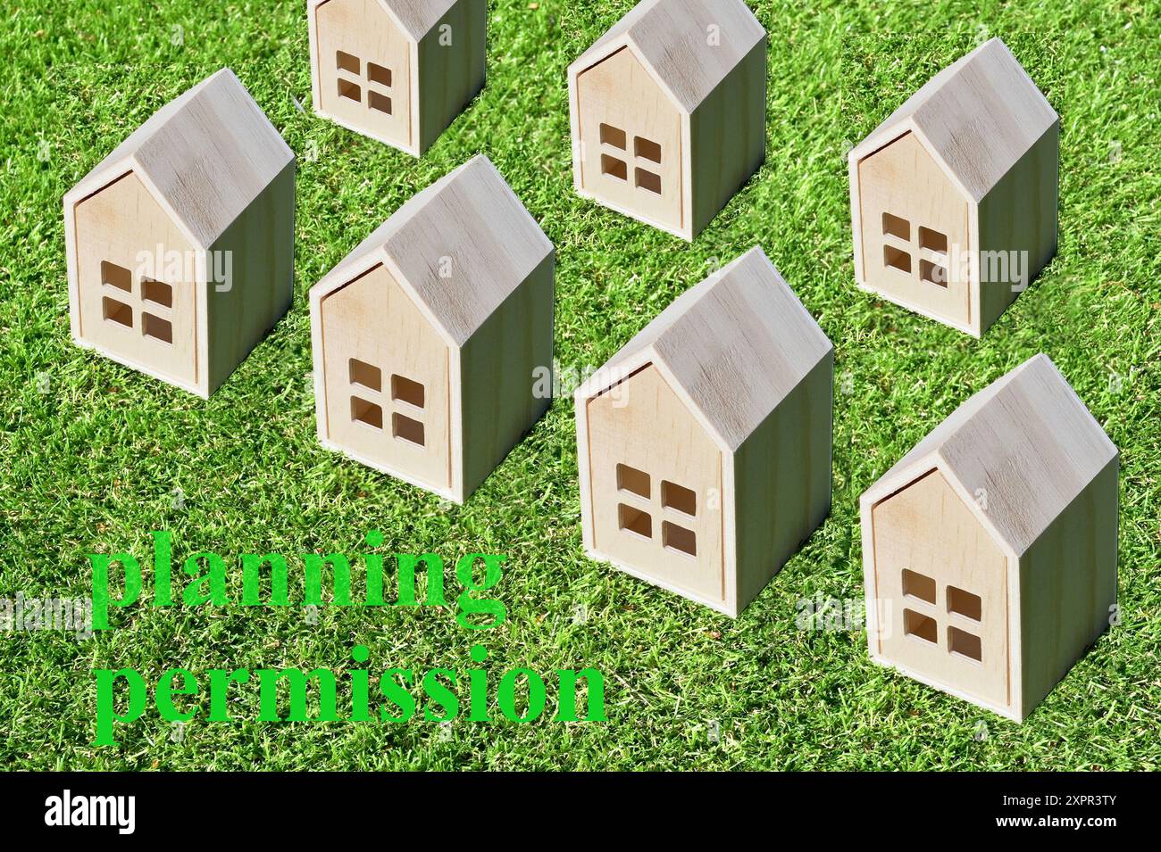 Kleine Modellhäuser auf einem Hintergrund von kurzem grünem Gras. Baugenehmigung für den Hausbau nach Grüngürtelkonzept. No People Neues Wohnkonzept. Stockfoto