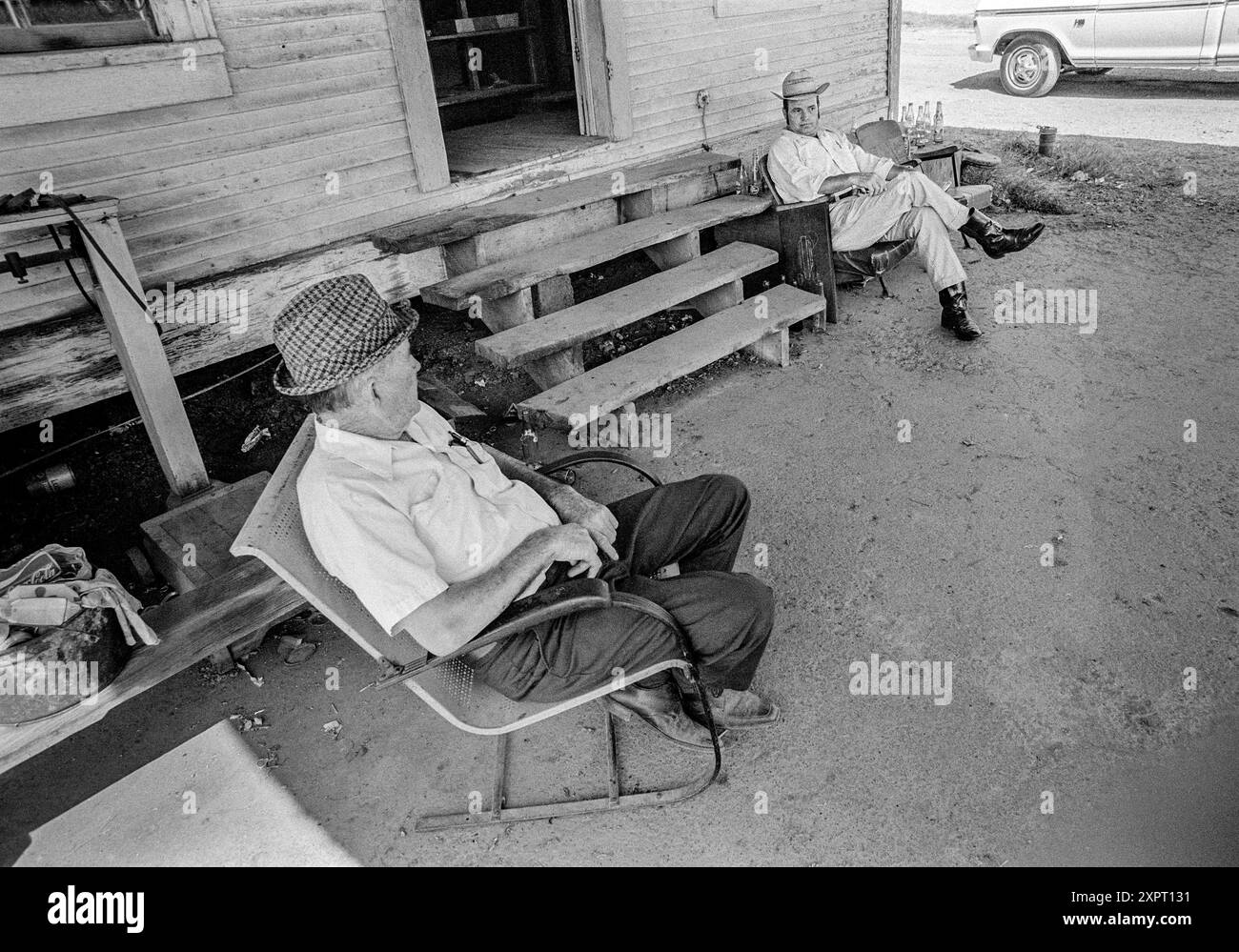 Mazedonien, Arkansas, USA – 23. Juni 2024: Horizontale Aufnahme eines Vaters und Sohnes, die 1975 vor Dads altes Landhaus sitzen. Stockfoto