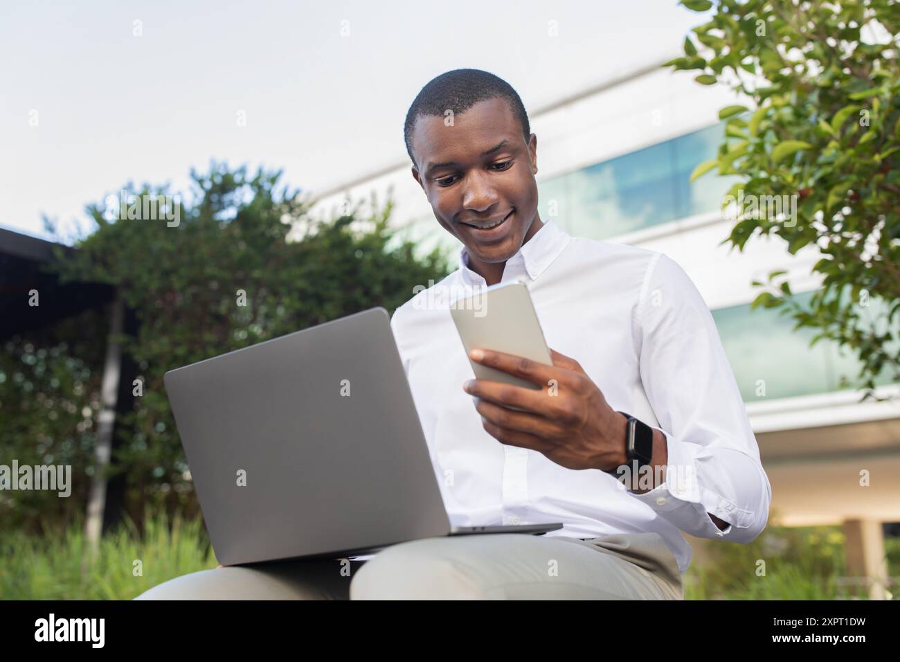 Junger Mitarbeiter, der sich mit Fernarbeiten beschäftigt, während er die Umgebung im Freien genießt Stockfoto