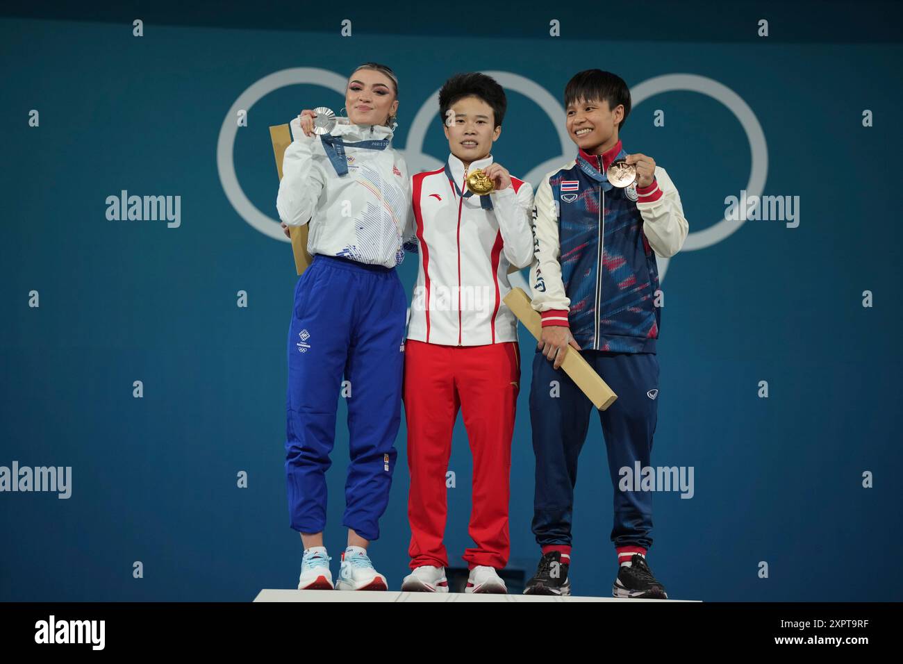 Medalist, from left to right, Michaela Valentina Cambei of Romania, silver, Hou Zhihui of China, gold, and Surodchana Khambao of Thailand, bronze, celebrate on the podium during the medal ceremony for the women's 49kg weightlifting event at the 2024 Summer Olympics, Wednesday, Aug. 7, 2024, in Paris, France. (AP Photo/Kin Cheung) Stockfoto
