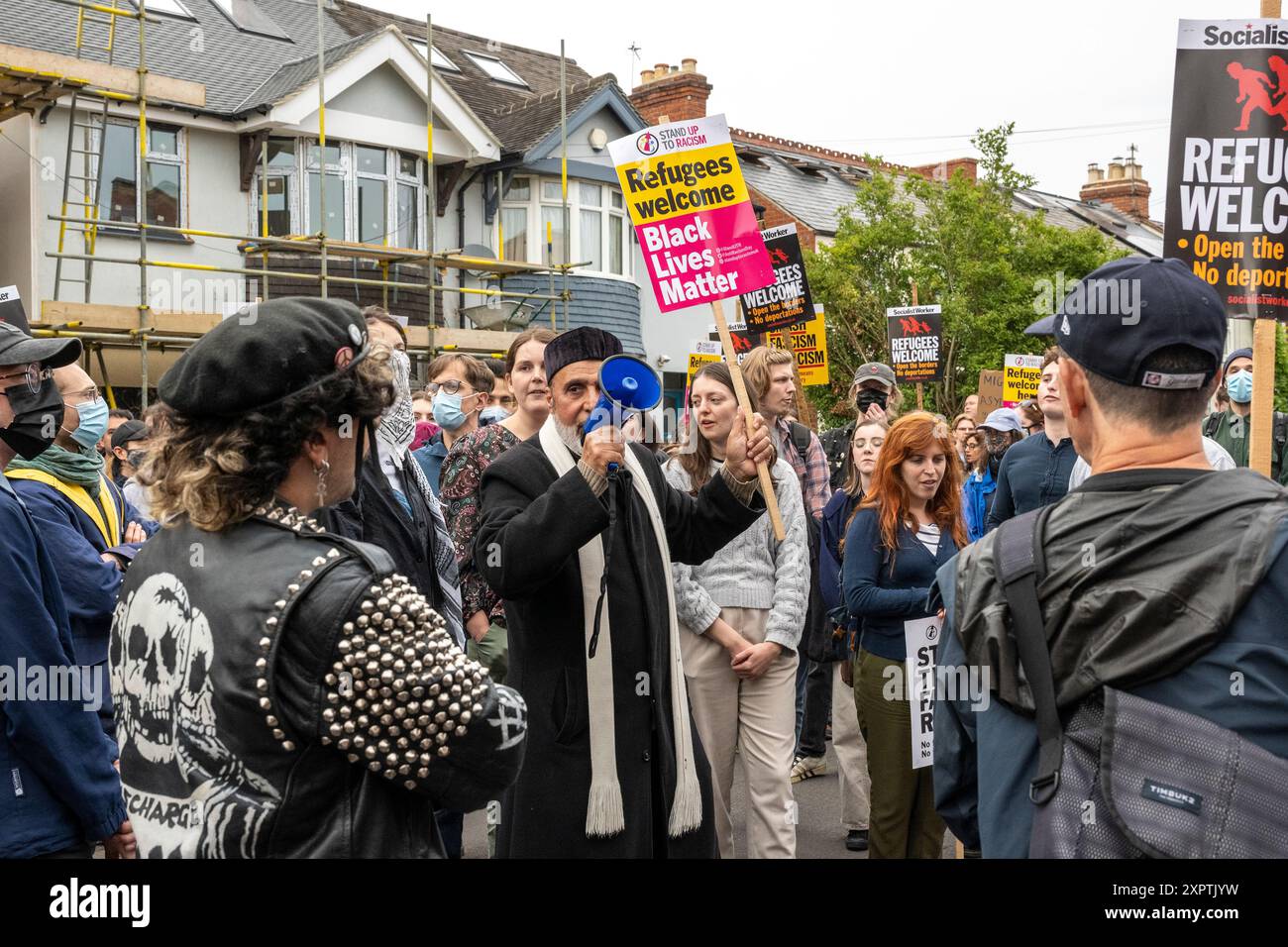 Dr. Sheikh Ramzy vom Oxford Islamic Information Centre führte Gesang und Gesänge von Hunderten von Anti-Rassismus-Demonstranten, die sich versammelten, um einen Schutzschild vor dem Asylum Welcome Centre an der Magdalen Road im Osten von Oxford zu bilden. Chanten und Singen zur Unterstützung von Flüchtlingen und Einwanderern angesichts der Gerüchte, dass am Mittwochabend rechtsextreme Aktionen angekündigt wurden. Stockfoto