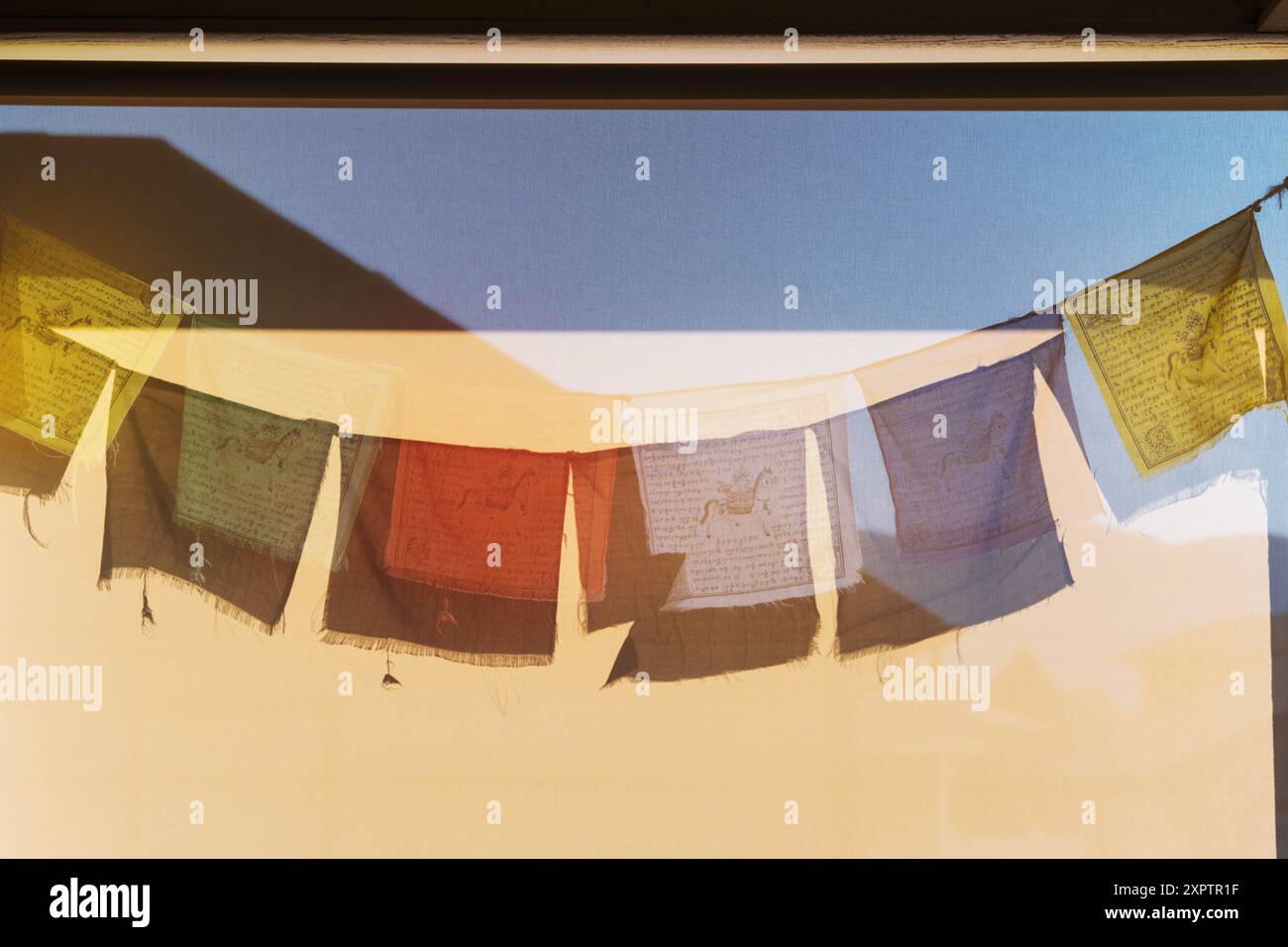 Sonne wirft Schatten der traditionellen buddhistischen Gebetsfahnen auf ein Windschutz Stockfoto
