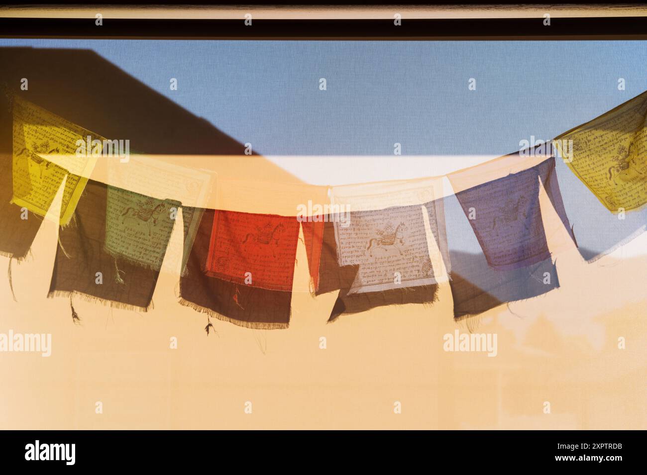 Sonne wirft Schatten der traditionellen buddhistischen Gebetsfahnen auf ein Windschutz Stockfoto