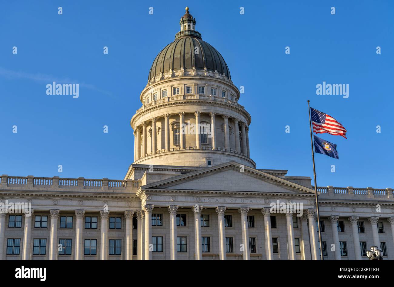 Utah State Capitol – Nahansicht der Kuppel und Fassade des Utah State Capitol Building, mit nationalen und staatlichen Flaggen im Vorfeld, Salt Lake City, UT. Stockfoto