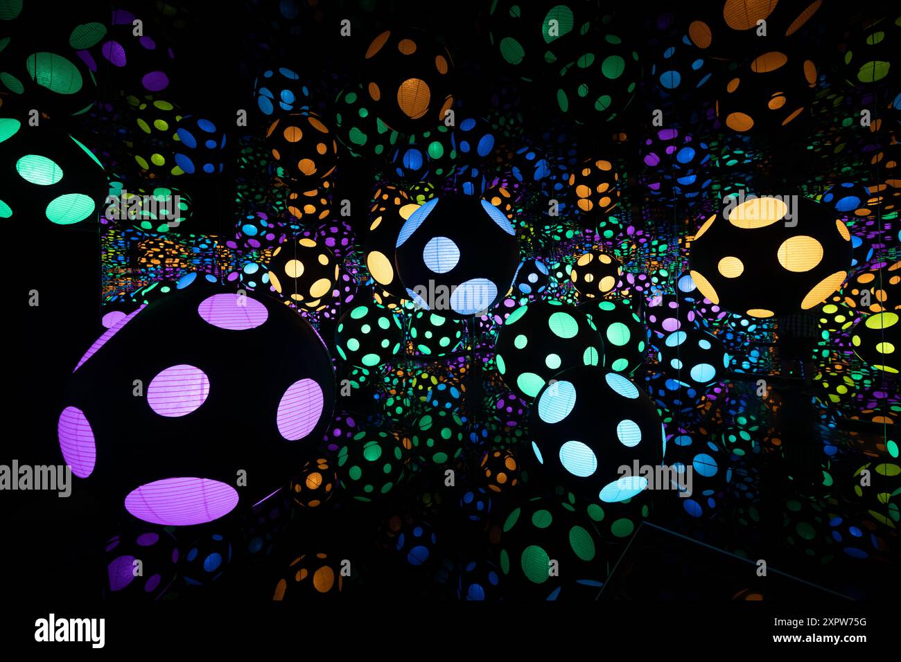 Yayoi Kusama Infinity Mirror Room Hirshhorn Museum Washington D.C. | WASHINGTON D.C., Vereinigte Staaten – Dutzende von gepunkteten Papierlaternen hängen in einer Spiegelkammer in Yayoi Kusamas Infinity Mirror Room im Hirshhorn Museum. Die reflektierenden Oberflächen wiederholen die leuchtenden Kugeln zu einer Illusion von endlosem Raum, ein charakteristischer Effekt, den der japanische Künstler seit den 1960er Jahren verfeinert hat Die Installation erscheint in „One with Eternity: Yayoi Kusama in the Hirshhorn Collection“. Stockfoto