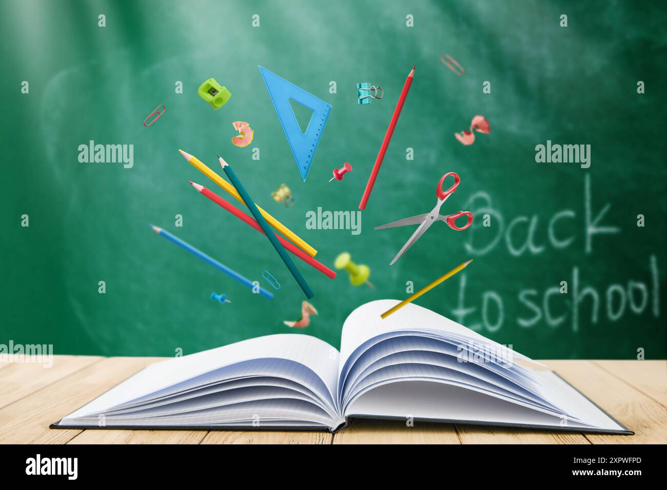 Bleistifte, Lineal, Spitzer, Späne und Scheren Schulutensilien fliegen aus dem offenen schwarzen Cover Buch auf dem Hintergrund des Schulgrüntafels mit Sonnenstrahlen. B Stockfoto