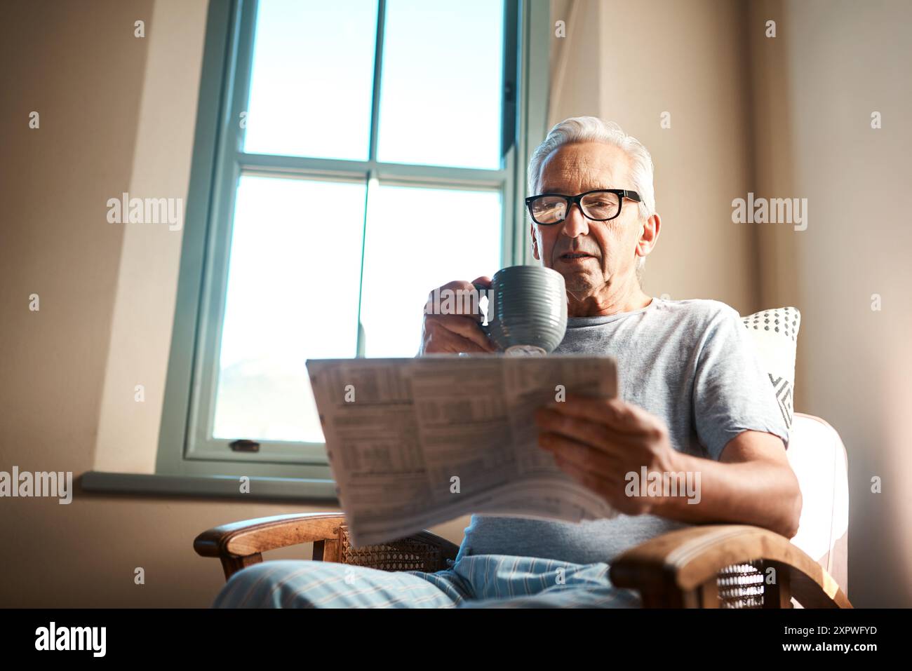 Senior, Mann und Zeitung zum Lesen mit Kaffee, Morgenroutine und Tagesartikel mit Relax zur Information. Person, Getränk und Zuhause mit Stockfoto