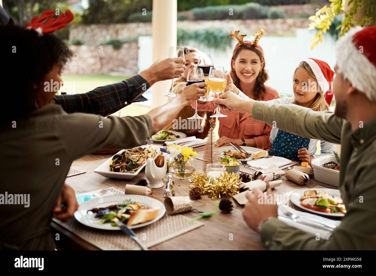 Familie, Glas und Toast zu Weihnachten, Feier und Mittagessen im Freien mit Speisen, Anfeuerungen und Getränken im Hinterhof. Mom, Dad und Kinder im Urlaub Stockfoto