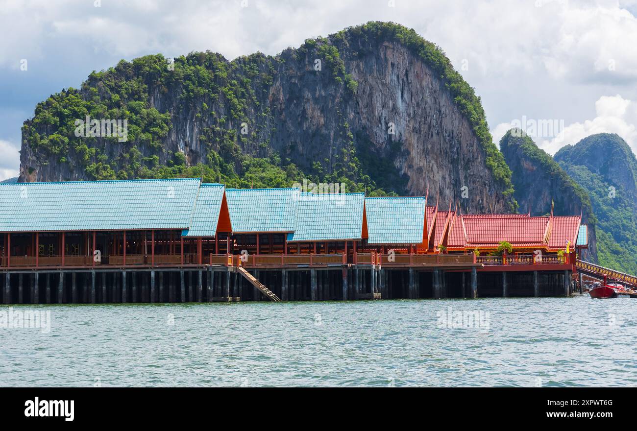 Blick auf das Fischerdorf Nga auf der Insel Koh Panyee, Thailand Phuket, an einem sonnigen Tag. Wunderschöne traditionelle thailändische Häuser mit Berg und blauem Himmel mit Clou Stockfoto