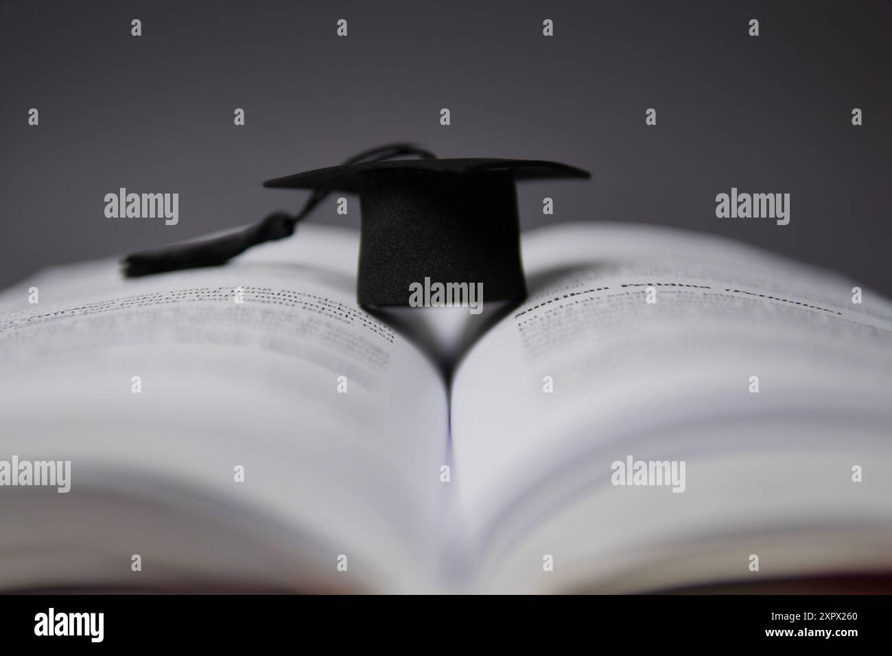 Eine schwarze Graduierungsmütze auf einem offenen Buch. Bildung, Wissenskonzept. Stockfoto