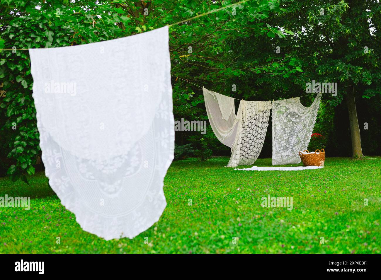 Weiße Wäsche auf Wäscheleinen im Garten. Weiße Vorhänge trocknen in der Sonne. Stockfoto