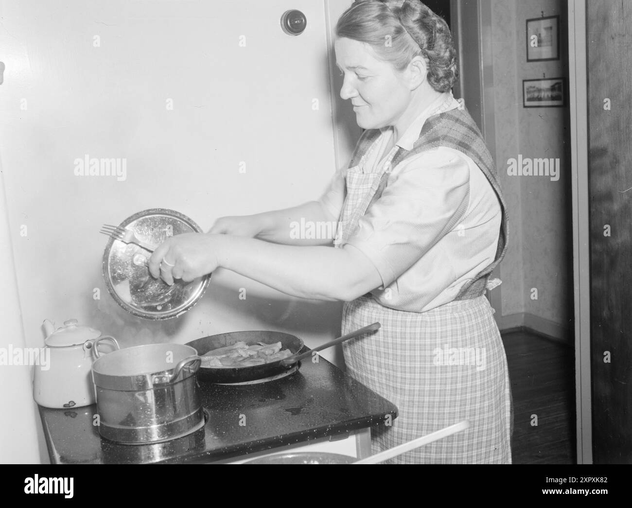 Aktuell 13-1948: Frauen, die Doppelleben führen Doppelarbeitende Frauen. Sie nehmen am Berufsleben Teil und sind auch Hausfrauen. Die Textilarbeiterin Frau Else Lund hat keine Zeit, sich langweilen zu lassen. Sie ist um halb fünf Uhr morgens auf und bereitet das Frühstück für ihren Mann vor, der vor sechs zur Arbeit gehen muss. Sie haben zwei Söhne, einen vier und einen achteinhalb. Der jüngste ist in der Tagesbetreuung, wenn die Mutter in der Fabrik ist, von acht bis sechzehn. Der Achtjährige geht um halb acht zur Schule. Mrs. Lund hat kein Dienstmädchen, also braucht man nicht viel Fantasie, um zu verstehen, dass sie es nicht tut. Stockfoto