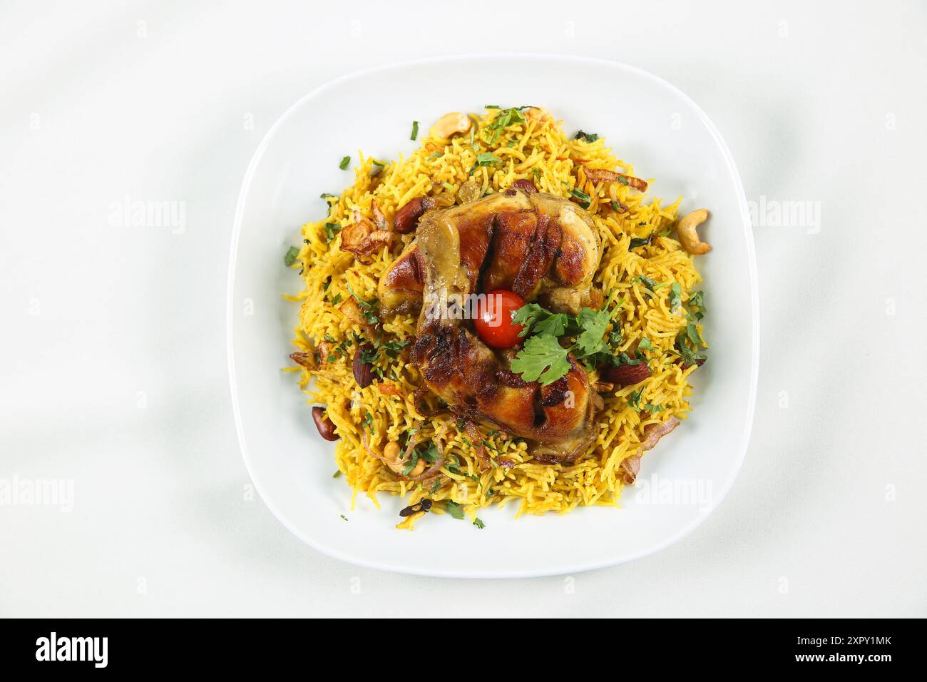 Arabische Küche; Hühnchen 'Kabsa' oder Hühnchen Biryani Reis. Serviert mit goldgebratenen Zwiebeln, knusprigen gerösteten Nüssen und Rosinen, frischer Petersilie, Stockfoto