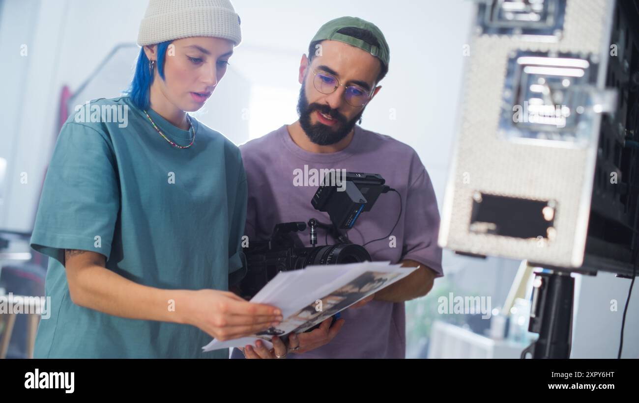 Junge kaukasische weibliche und männliche Kameramann*innen aus dem Nahen Osten schreiben Ein Drehbuch Einer Kamera auf Einem vielbeschäftigten Filmset, wobei der Schwerpunkt auf der Videoproduktion für Eine Dokumentarfilm- oder Fernsehshow liegt. Stockfoto