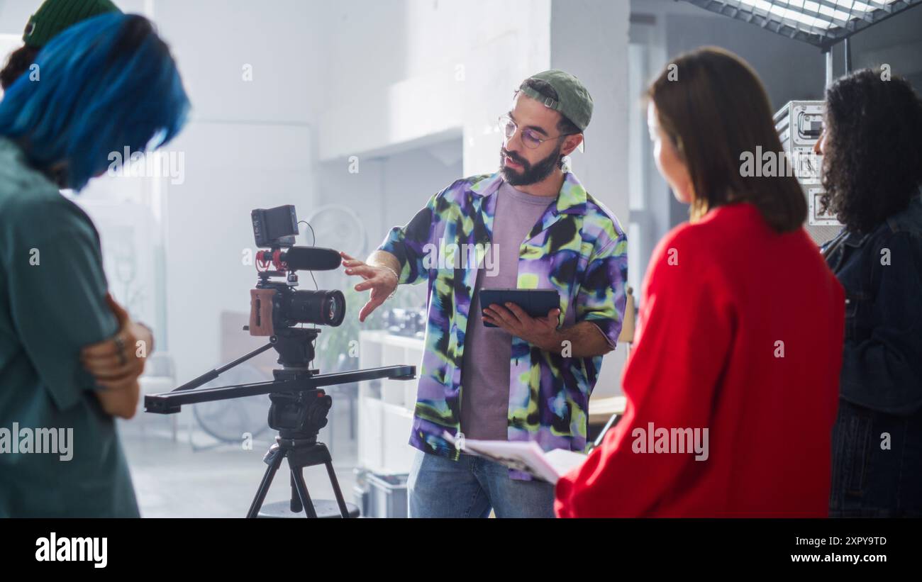 Das Young diverse Team arbeitet an Einem Filmset zusammen, wobei Ein männlicher Latin Director das Shooting leitet, umgeben von Einer Kamera und einer Crew in Einem hell beleuchteten Studio, das sich auf Teamwork und Kreativität konzentriert. Stockfoto