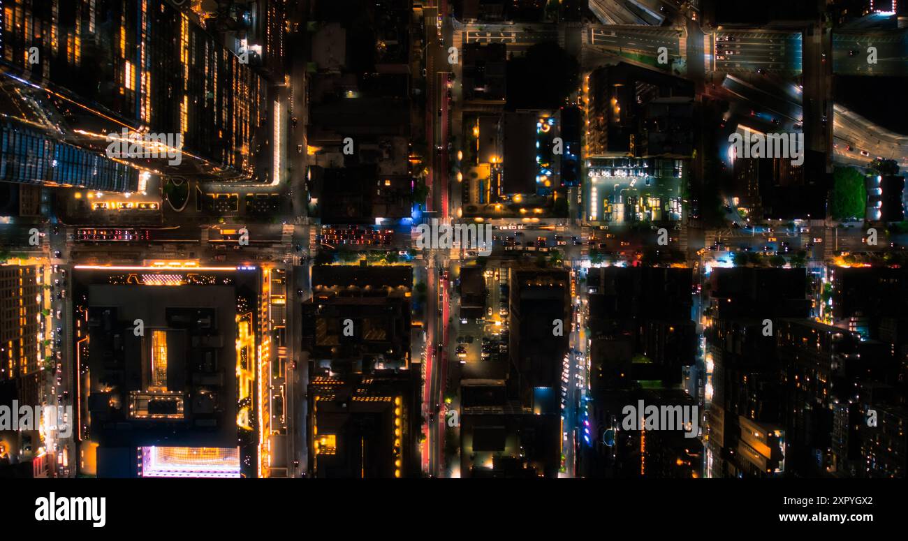 Filmaufnahmen In Der Hubschraubernacht, Die Sich Diagonal Über Dem New York City Avenue Grid System Bewegen. Top-Down-Luftbild von überfüllten Straßen, Straßen, Autos, Nachtleben und hohen modernen Wolkenkratzern Stockfoto