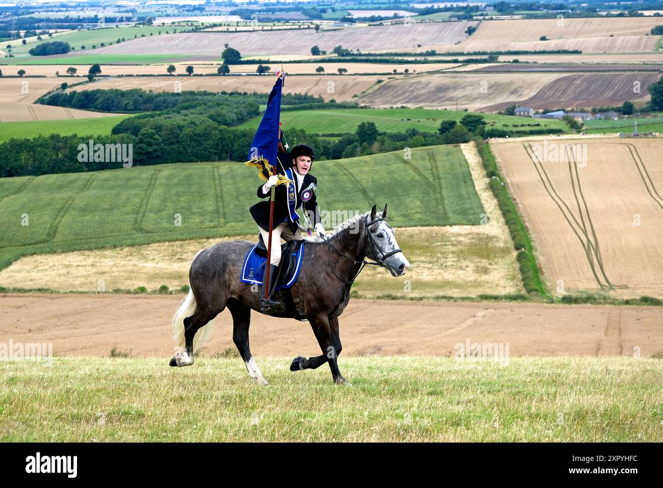 Coldstream, Großbritannien. August 2024. Coldstream Civic Week - Flodden Rideout als Teil der Coldstream Civic Week der jährliche Ritt zum Schauplatz der Schlacht von Flodden (9. September 1513) auf Branxton Hill trägt der Coldstreamer Mr. Jake Kerr den Stadtstandard und galoppiert am Ort der Schlacht auf Branxton Hill. es folgten fast 200 Anhänger. (Quelle: Rob Gray/Alamy Live News Stockfoto