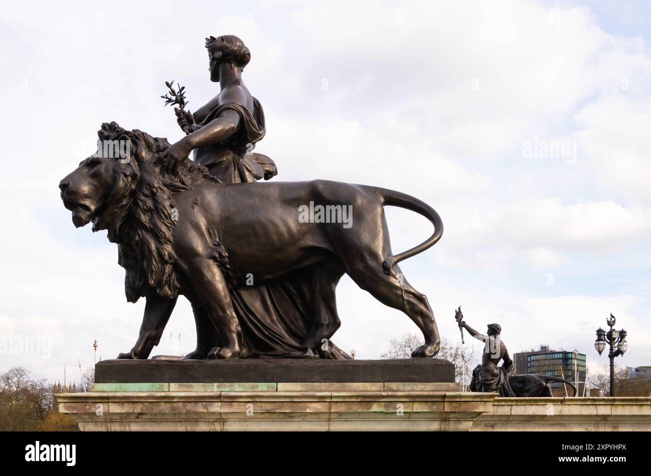 Bronzestatue des Friedens, unterstützt von einem bronzenen Löwen, mit der Figur des Fortschritts im Hintergrund, Victoria Memorial, The Mall, London, England Stockfoto