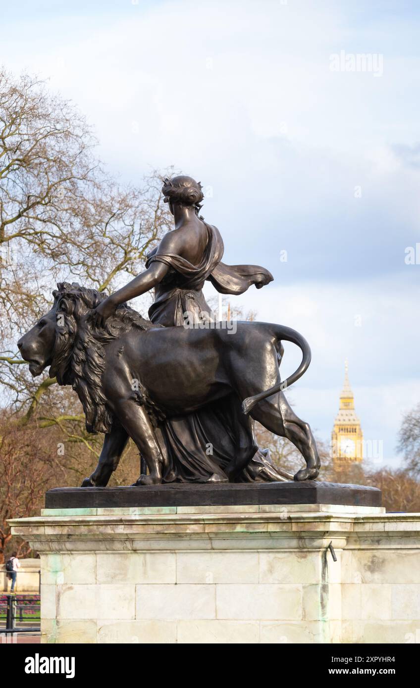 Bronzestatue des Friedens, unterstützt von einem bronzenen Löwen, mit Big Ben im Hintergrund, Victoria Memorial, The Mall, London, England Stockfoto