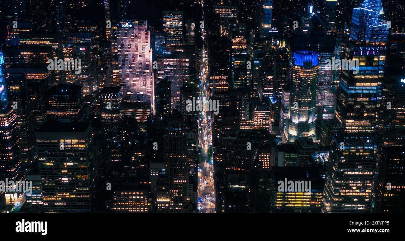 Kinoaufnahmen in der Luftaufnahme, die das Nachtleben von NYC einfangen. Hubschrauber. Blick von oben nach unten auf die Straßen der Stadt mit Autos und Taxis, Fußgänger auf Kreuzungen, Fahrradfahrer auf Busspuren Stockfoto