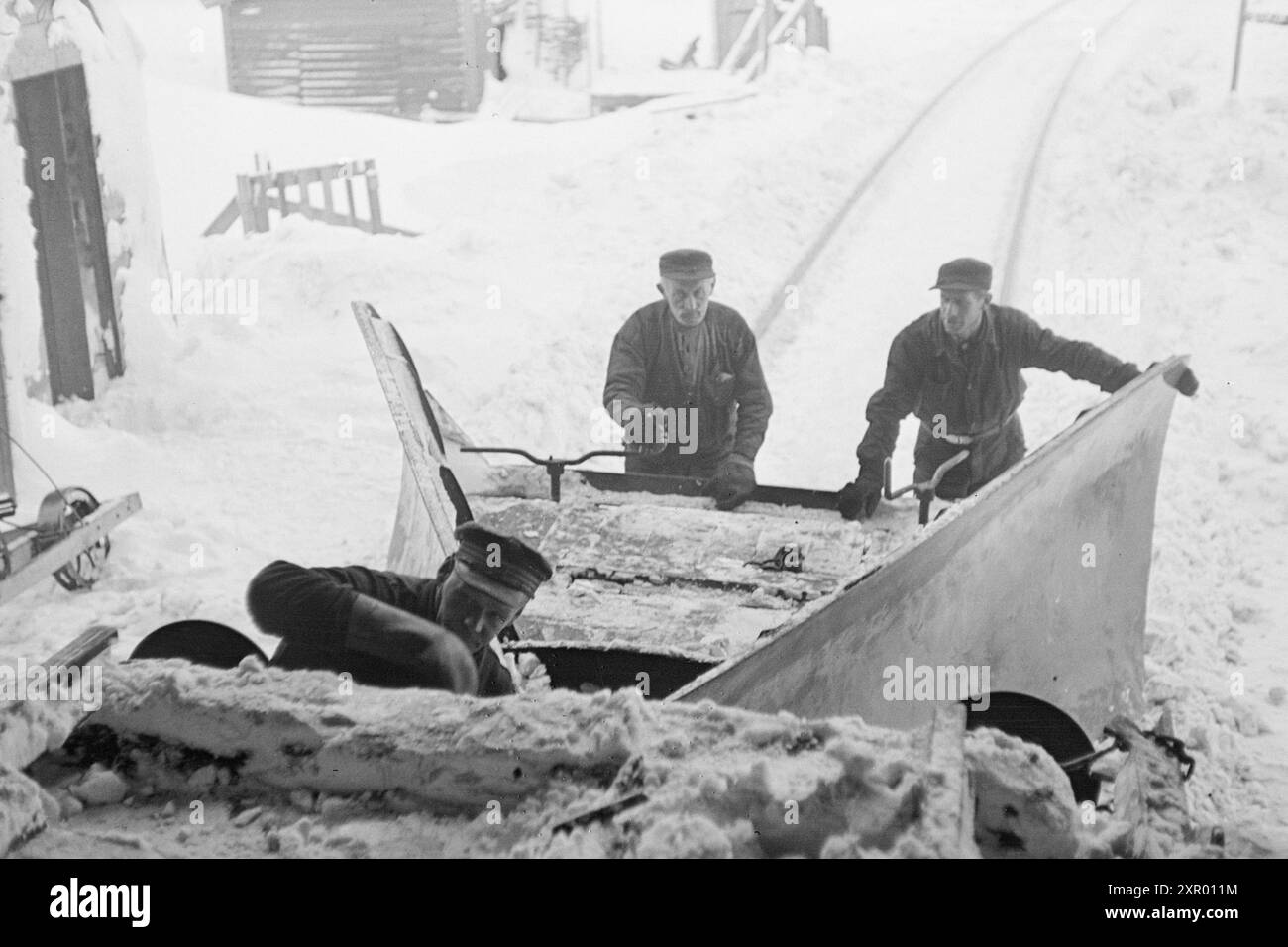Tatsächlich 1948: Schneeräumung auf der Bergen Railway. Die Bergen Railway, eine der wichtigsten Eisenbahnlinien Norwegens, erreicht ihren höchsten Punkt westlich von Finse auf 1301 Metern über dem Meeresspiegel. Wind und Schnee sorgen hier dafür, dass es nicht immer so einfach ist, diese Strecke im Winter offen zu halten. Nachdem der rotierende Schneepflug und der „Scraper“ die Linie bearbeitet haben, wird eine schöne und gleichmäßige Straße ausgegraben. Aber die Gleise sind dann mehr oder weniger mit Schnee bedeckt. Jetzt ist es Zeit für den Kettenreiniger, der so konstruiert ist, dass er tief genug zwischen den Schienen gräbt und sie auch von Schnee reinigt. Die Spur Stockfoto
