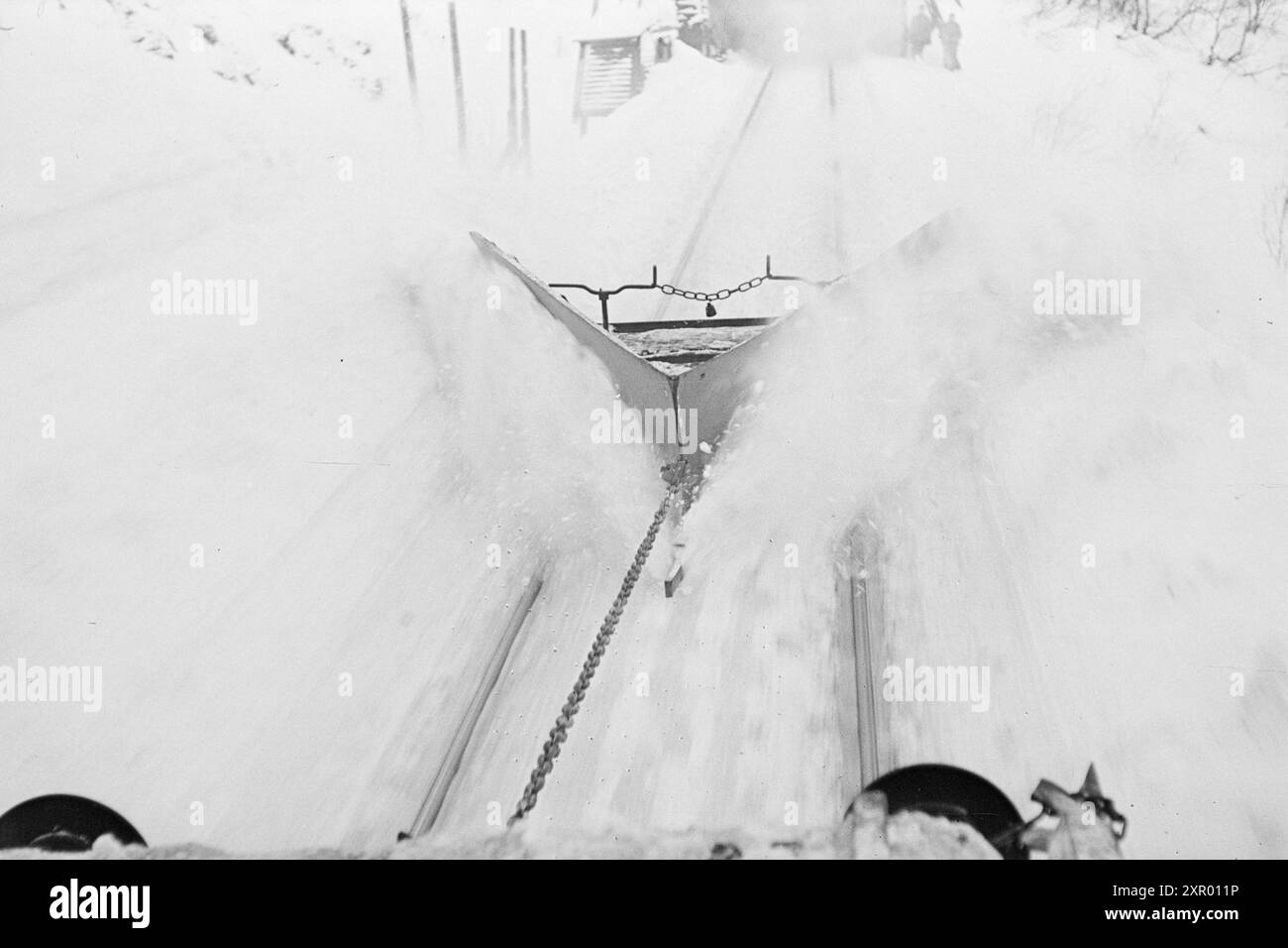 Tatsächlich 1948: Schneeräumung auf der Bergen Railway. Die Bergen Railway, eine der wichtigsten Eisenbahnlinien Norwegens, erreicht ihren höchsten Punkt westlich von Finse auf 1301 Metern über dem Meeresspiegel. Wind und Schnee sorgen hier dafür, dass es nicht immer so einfach ist, diese Strecke im Winter offen zu halten. Nachdem der rotierende Schneepflug und der „Scraper“ die Linie bearbeitet haben, wird eine schöne und gleichmäßige Straße ausgegraben. Aber die Gleise sind dann mehr oder weniger mit Schnee bedeckt. Jetzt ist es Zeit für den Kettenreiniger, der so konstruiert ist, dass er tief genug zwischen den Schienen gräbt und sie auch von Schnee reinigt. Die Spur Stockfoto