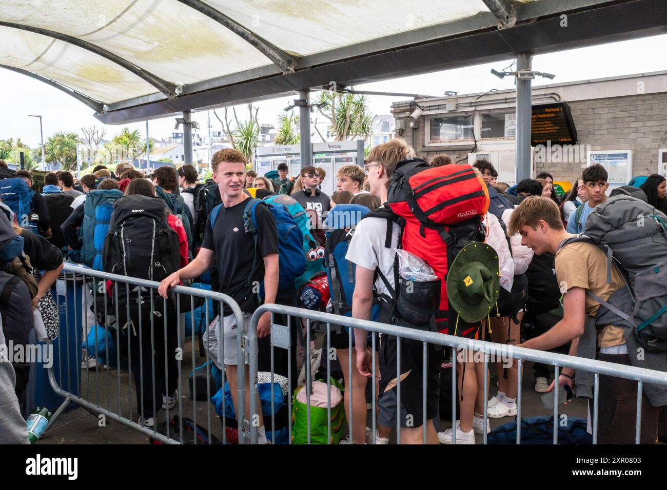 Einige der 1400 aufgeregten jungen Leute standen geduldig in der Warteschlange, nachdem sie mit einem Zug am Bahnhof Newquay zum Boardmasters Festival in Newquay angekommen waren Stockfoto