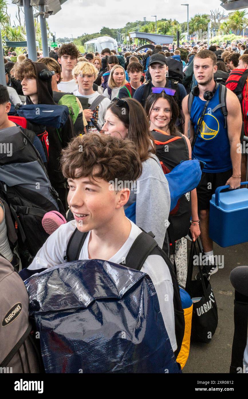 Einige der 1400 aufgeregten jungen Leute standen geduldig in der Warteschlange, nachdem sie mit einem Zug am Bahnhof Newquay zum Boardmasters Festival in Newquay angekommen waren Stockfoto