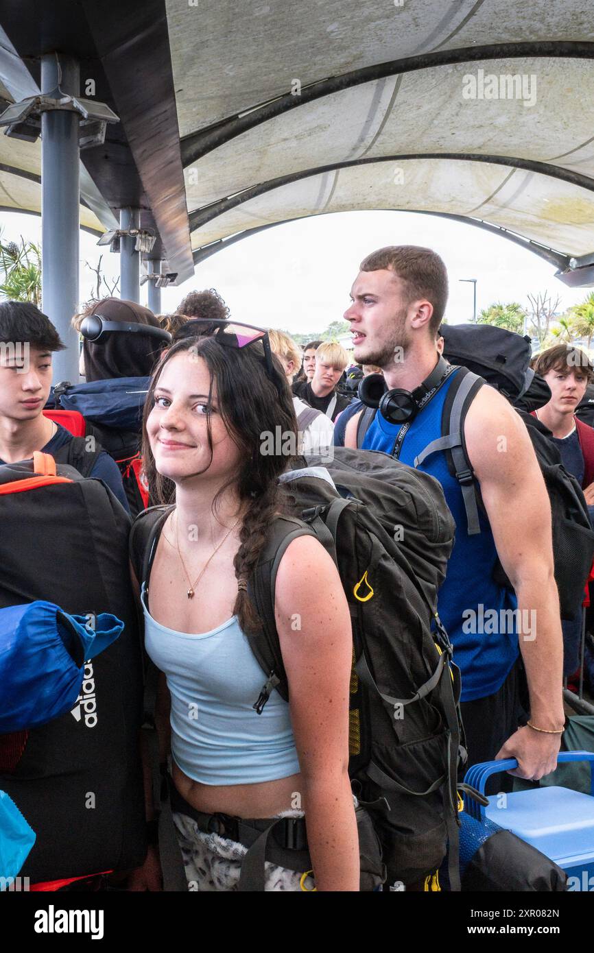 Einige der 1400 aufgeregten jungen Leute standen geduldig in der Warteschlange, nachdem sie mit einem Zug am Bahnhof Newquay zum Boardmasters Festival in Newquay angekommen waren Stockfoto