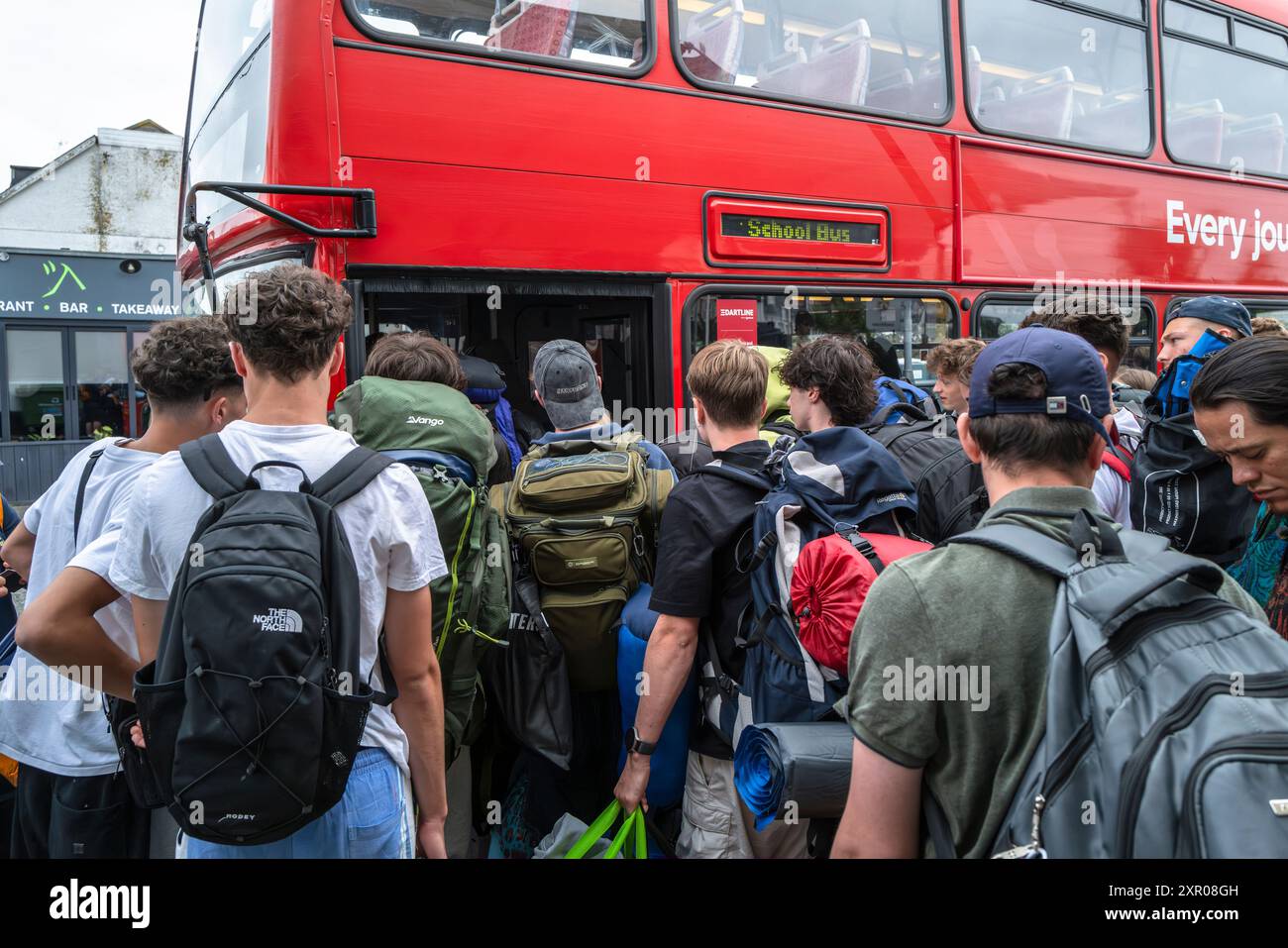 Junge Leute, die sich an Bord von Bussen anstellen, um sie zum Boardmasters Festival Newquay in Cornwall in Großbritannien zu bringen. Stockfoto