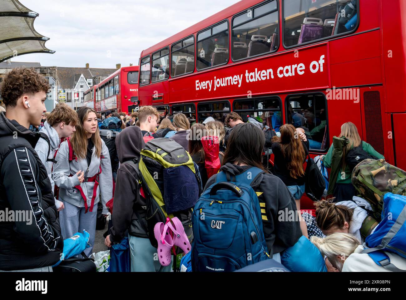 Junge Leute, die sich an Bord von Bussen anstellen, um sie zum Boardmasters Festival Newquay in Cornwall in Großbritannien zu bringen. Stockfoto