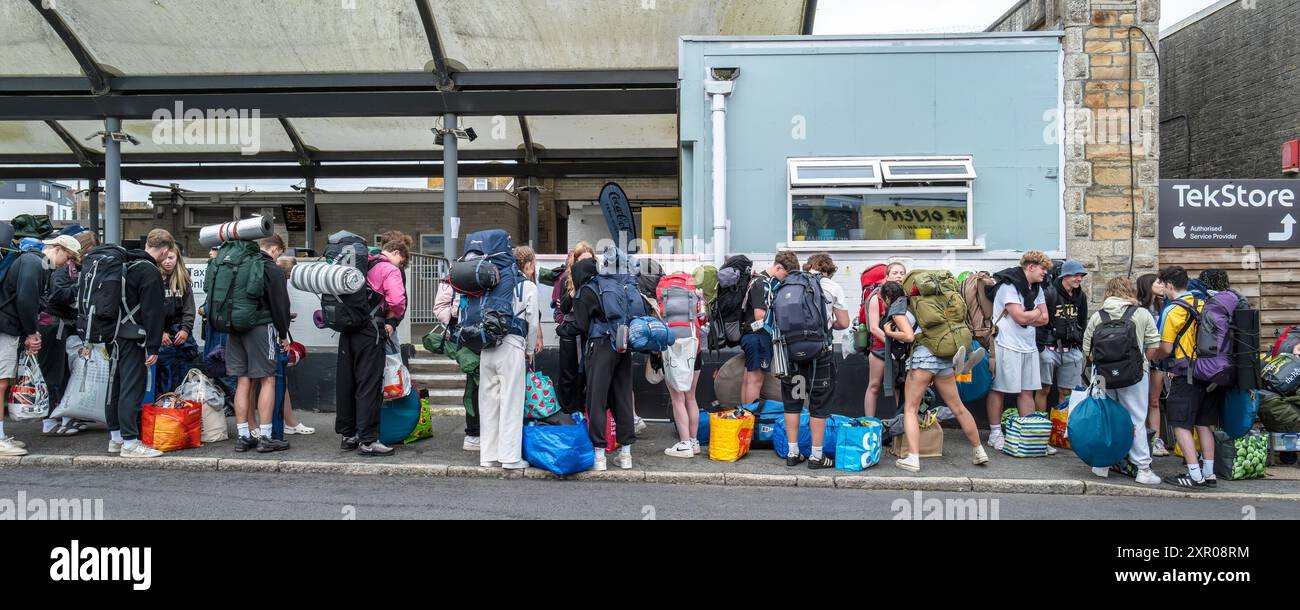 Ein Panoramablick von jungen Menschen, die sich an Bord von Bussen schlangen, um sie zum Boardmasters Festival Newquay in Cornwall in Großbritannien zu bringen. Stockfoto