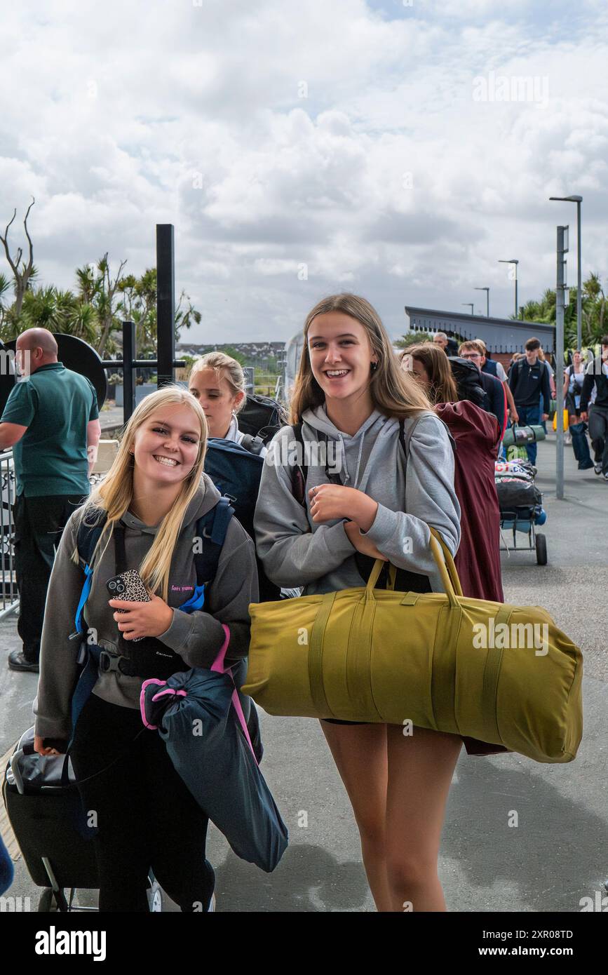 Einige der 1400 aufgeregten jungen Leute standen geduldig in der Warteschlange, nachdem sie mit einem Zug am Bahnhof Newquay zum Boardmasters Festival in Newquay angekommen waren Stockfoto