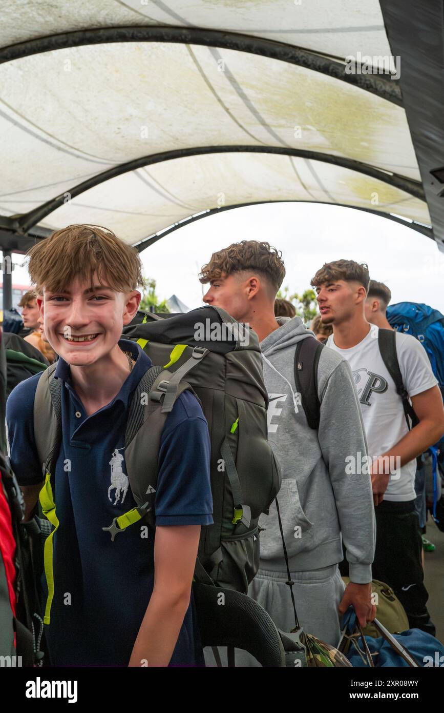 Begeisterte junge Leute, die am Bahnhof Newquay ankommen und sich an Bord der Busse schlangen, um sie zum Boardmasters Festival Newquay in Cornwall in Th zu bringen Stockfoto