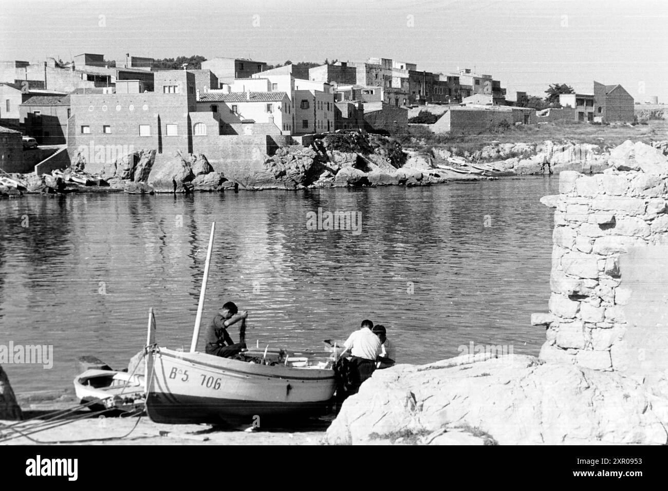 Männer kümmern sich um ein Fischerboot, das in der Bucht von L’Escala an Land liegt, Katalonien 1957. Männer kümmern sich um ein Fischerboot, das an Land in der Bucht von L'Escala, Katalonien 1957 liegt. Stockfoto