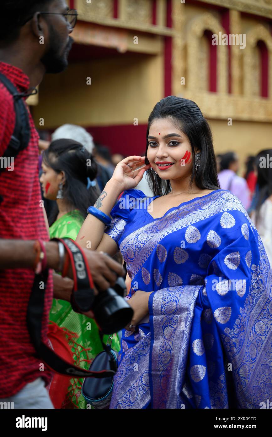 Porträt einer schönen jungen Frau, die eine traditionelle bengalische Festkleidung trägt und an Sindur Khela bei einem Puja-Pandal teilnimmt Stockfoto