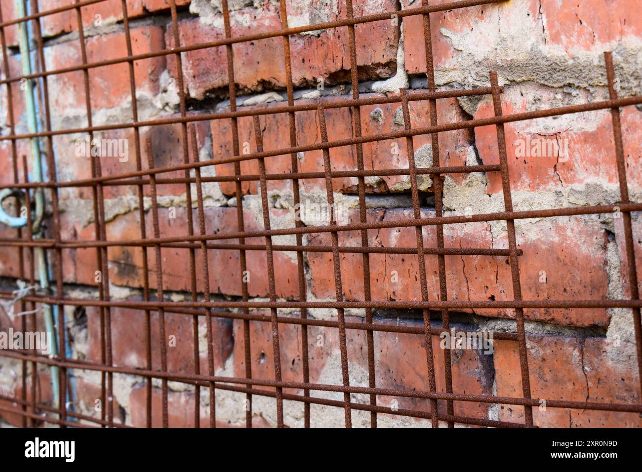 Ein Bild von Ziegelverkleidung an einer Wand mit rostigem Metallgitter Stockfoto