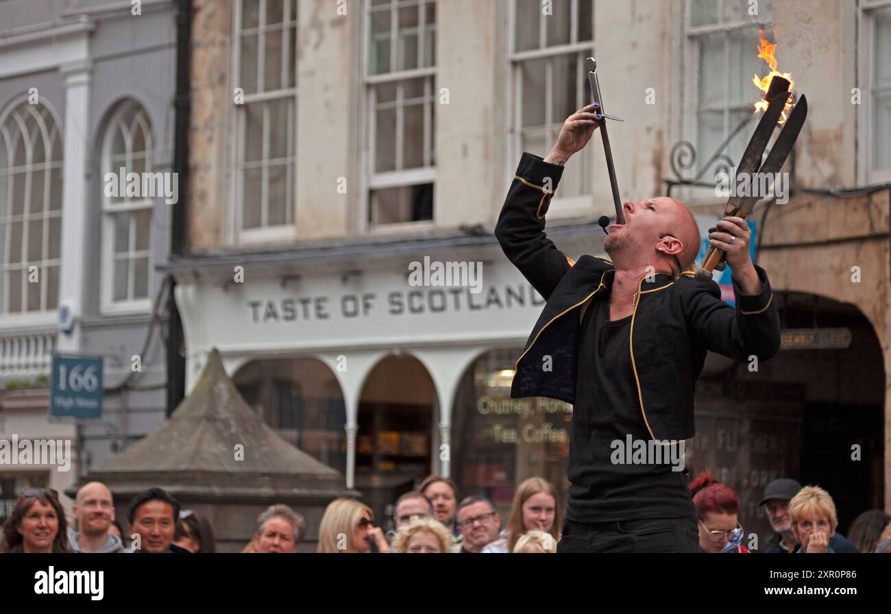 Royal Mile, Edinburgh, Schottland, Großbritannien. 8. August 2024. Dreich bewölkter Donnerstag auf der High Street für diejenigen, die Unterhaltung von den Street Performers suchen, um sie aufzumuntern. Im Bild: Tommy Fireboy schluckt ein Schwert und jongliert gleichzeitig mit Feuer. Quelle: Arch White/Alamy Live News. Stockfoto