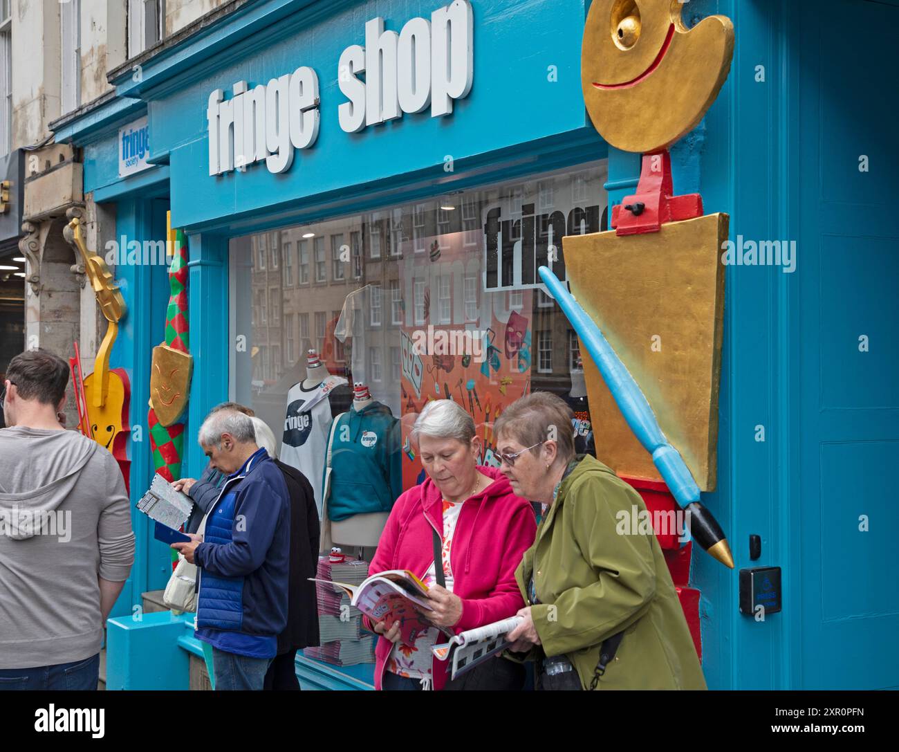 Royal Mile, Edinburgh, Schottland, Großbritannien. 8. August 2024. Dreich bewölkter Donnerstag auf der High Street für diejenigen, die Unterhaltung von den Street Performers suchen, um sie aufzumuntern. Abbildung: Peoplke Look in der Broschüre Fringe für interessante Shows. Quelle: Arch White/Alamy Live News. Stockfoto