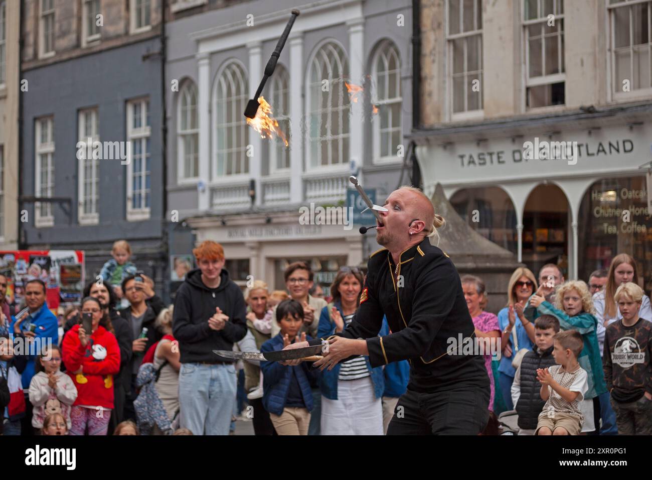 Royal Mile, Edinburgh, Schottland, Großbritannien. 8. August 2024. Dreich bewölkter Donnerstag auf der High Street für diejenigen, die Unterhaltung von den Street Performers suchen, um sie aufzumuntern. Im Bild: Tommy Fireboy schluckt ein Schwert und jongliert gleichzeitig mit Feuer. Quelle: Arch White/Alamy Live News. Stockfoto
