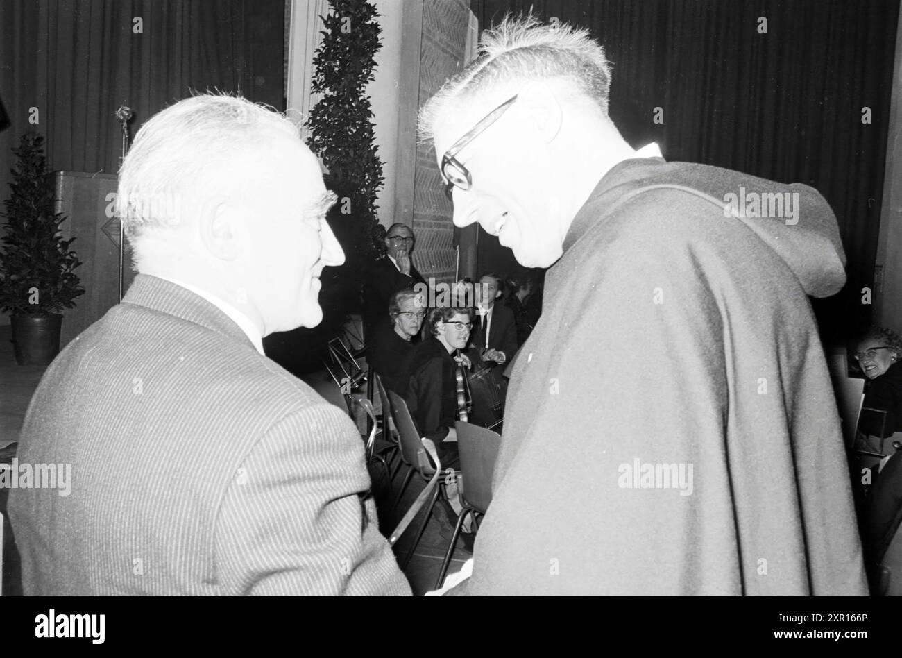 Treffen des katholischen Klerus in einem Gymnasium mit Glückwünschen von einem Priester, Whizgle Dutch News: Historische Bilder zugeschnitten auf die Zukunft. Erkunden Sie die Vergangenheit der Niederlande mit modernen Perspektiven durch Bilder von niederländischen Agenturen. Verbinden der Ereignisse von gestern mit den Erkenntnissen von morgen. Begeben Sie sich auf eine zeitlose Reise mit Geschichten, die unsere Zukunft prägen. Stockfoto