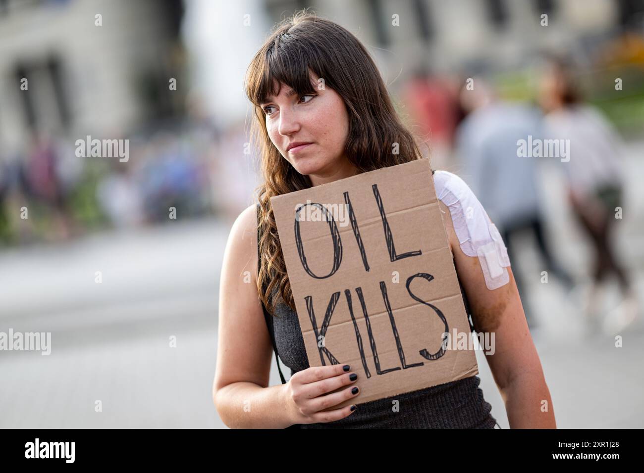 Berlin, Deutschland. August 2024. Carla Hinrichs, Klimaschutzaktivistin, nimmt als Reaktion auf die heutigen Polizeidurchsuchungen am Brandenburger Tor mit dem Banner „Öltötungen“ an der Letzten Generation Teil. Nach der Störaktion am Frankfurter Flughafen vor zwei Wochen wurden auf Veranlassung der Frankfurter Staatsanwaltschaft die Wohnungen von Mitgliedern der Klimagruppe der letzten Generation durchsucht und DNA-Proben entnommen. Quelle: Fabian Sommer/dpa/Alamy Live News Stockfoto