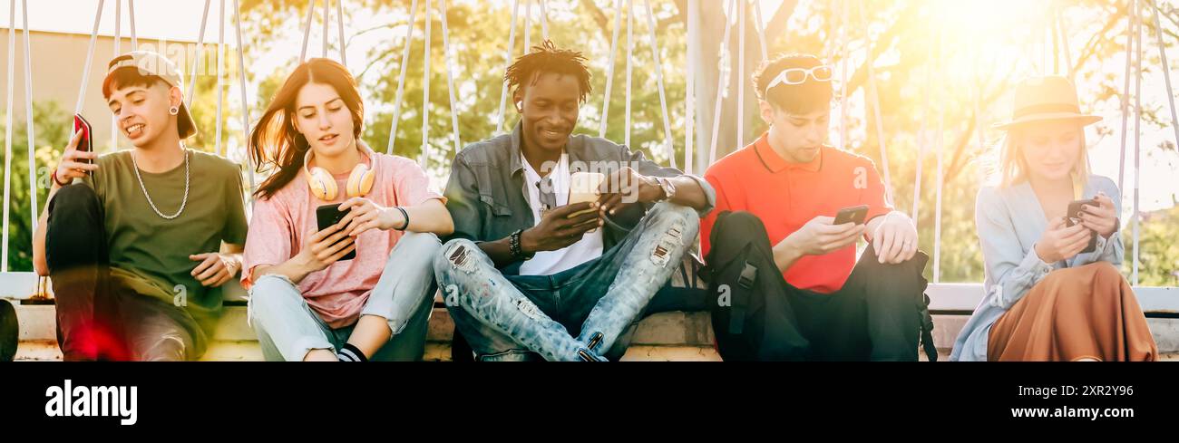 Eine Gruppe junger Millennials nutzt ihr Smartphone draußen, um Inhalte mit Freunden zu teilen – Jugend- und Technologiekonzept Stockfoto
