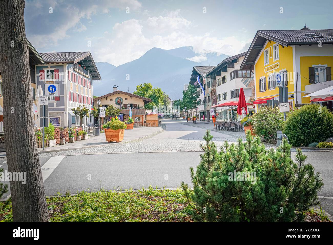 Garmisch-Partenkirchen, Bayern, Deutschland, Fußgängerzone, Alpenstadt, traditionelle Häuser, Bergkulisse, bewölkt, Gehweg, Straßenschilder, Verkehrsberuhigung, Tourismus, Gastronomie, Außensitzplätze, Pflanzenkübel, Blumendekoration, Fahrradweg, Fußgängerzone-Schild, Bergpanorama, Sommerwetter, ruhige Atmosphäre, lokale Geschäfte, Besucher, Urbanität, Nachhaltigkeit, Klimawandel, Touristenattraktion, ländliche Idylle, Erholung, Architektur, Umweltschutz, Dörferleben, Freizeitaktivitäten, Naturschutz, kulturelles Erbe. *** Garmisch Partenkirchen, Bayern, Deutschland, Fußgängerzone, Alpenstadt, Stockfoto