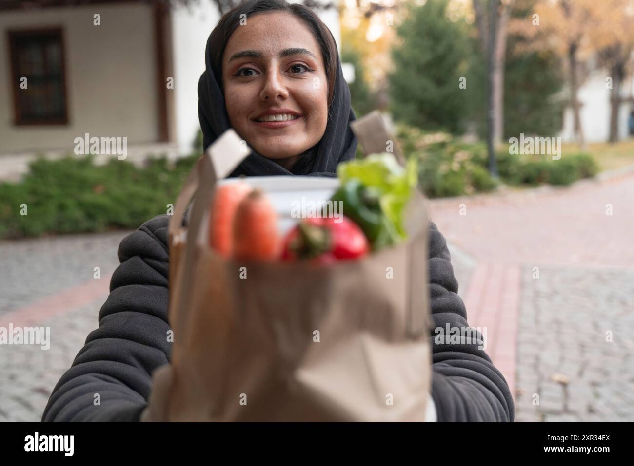 Nahöstliche Lieferung Mann trägt Gesichtsmaske in der Handhabung Beutel mit Lebensmitteln, Obst, Gemüse geben weiblichen Kunden vor dem Haus. express-Supermarkt Stockfoto